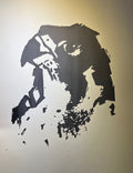 A high-contrast black ink image depicts the face of a peregrine falcon, with one eye and the beak clearly defined. The form is abstract and expressive, with splattered and broken edges . The background is a soft white, emphasizing the stark silhouette.